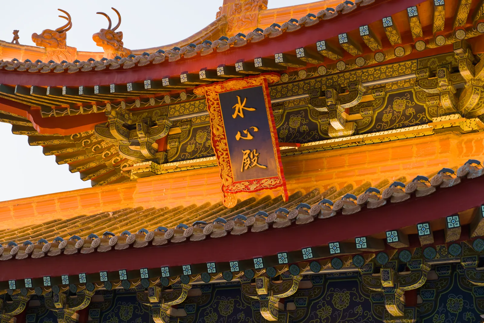 水心殿檐下仰拍：鎏金斗拱与青绿彩画之间悬着一块蓝底金字的竖匾，上写“水心殿”，屋顶铺黄琉璃瓦，屋脊上有龙形吻兽